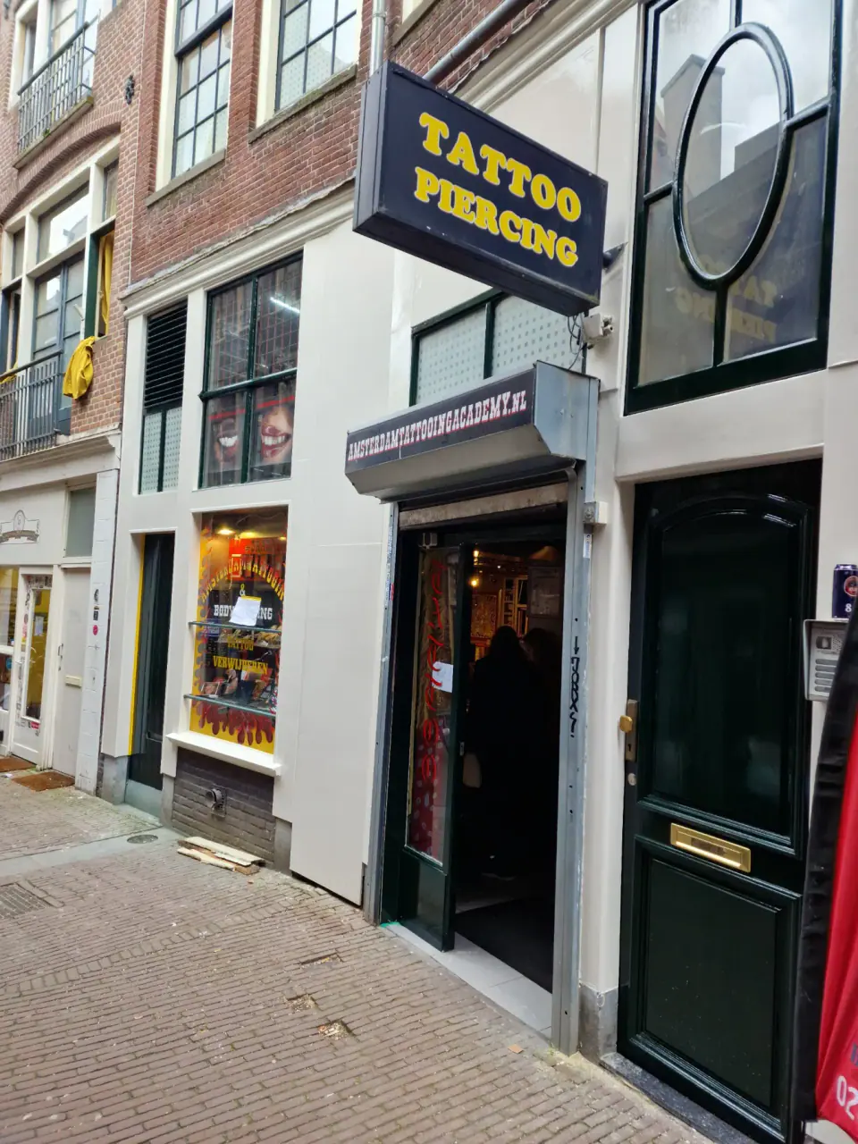 Nagenoeg afgeronde witte winkelgevel van Amsterdam Tattooing